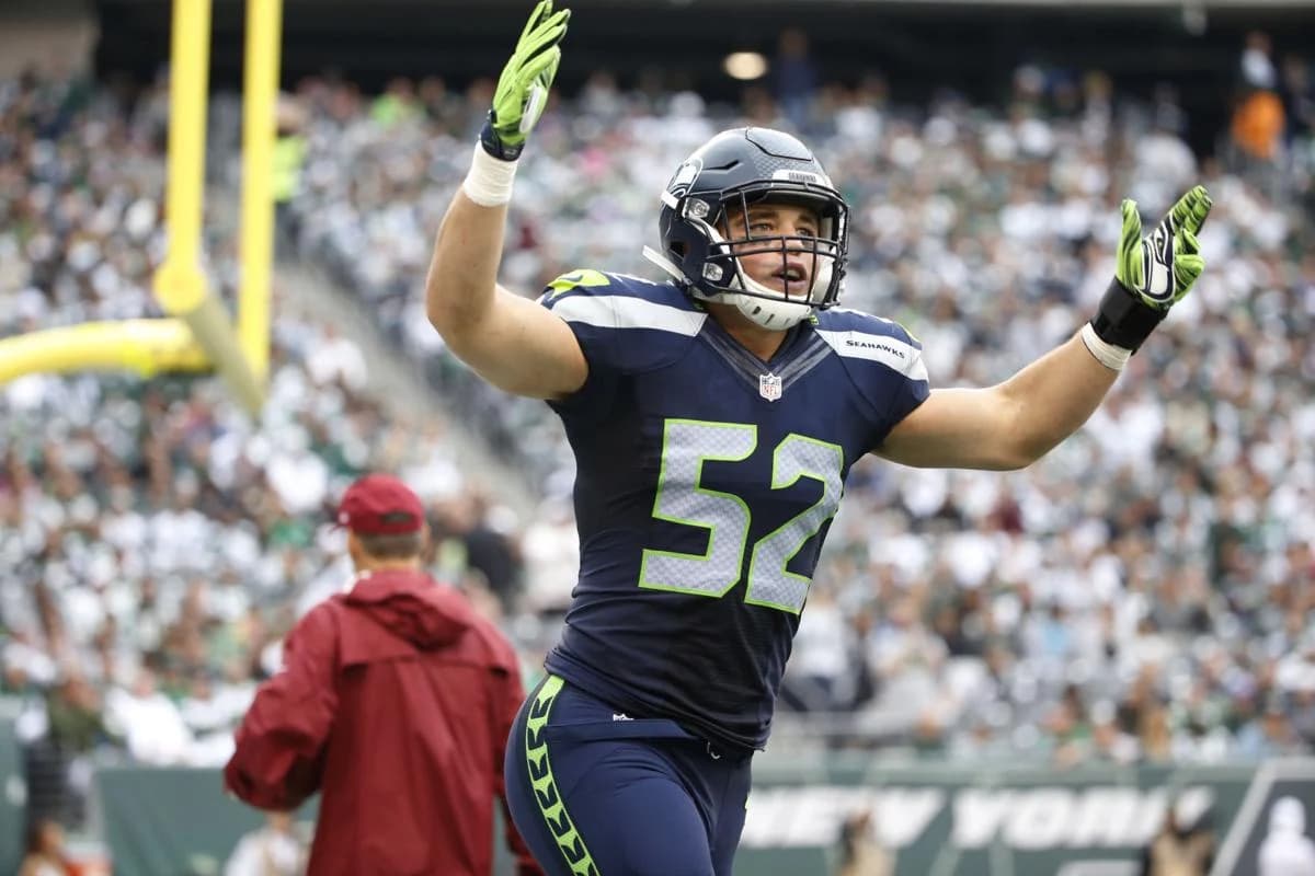 Brock Coyle in his Seattle Seahawks uniform, arms raised on the field