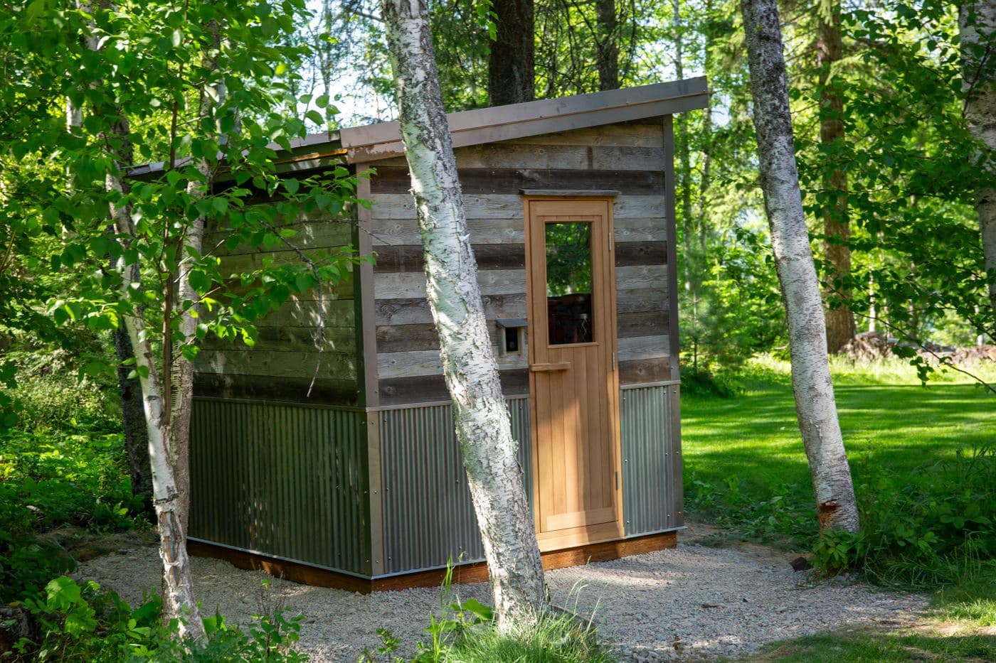 Custom reclaimed-wood sauna among birch trees