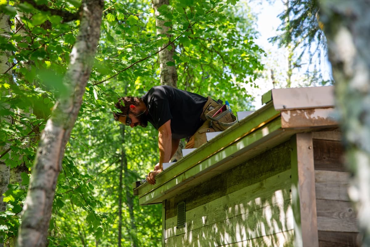 Builder on the roof fastening the metal roof edge