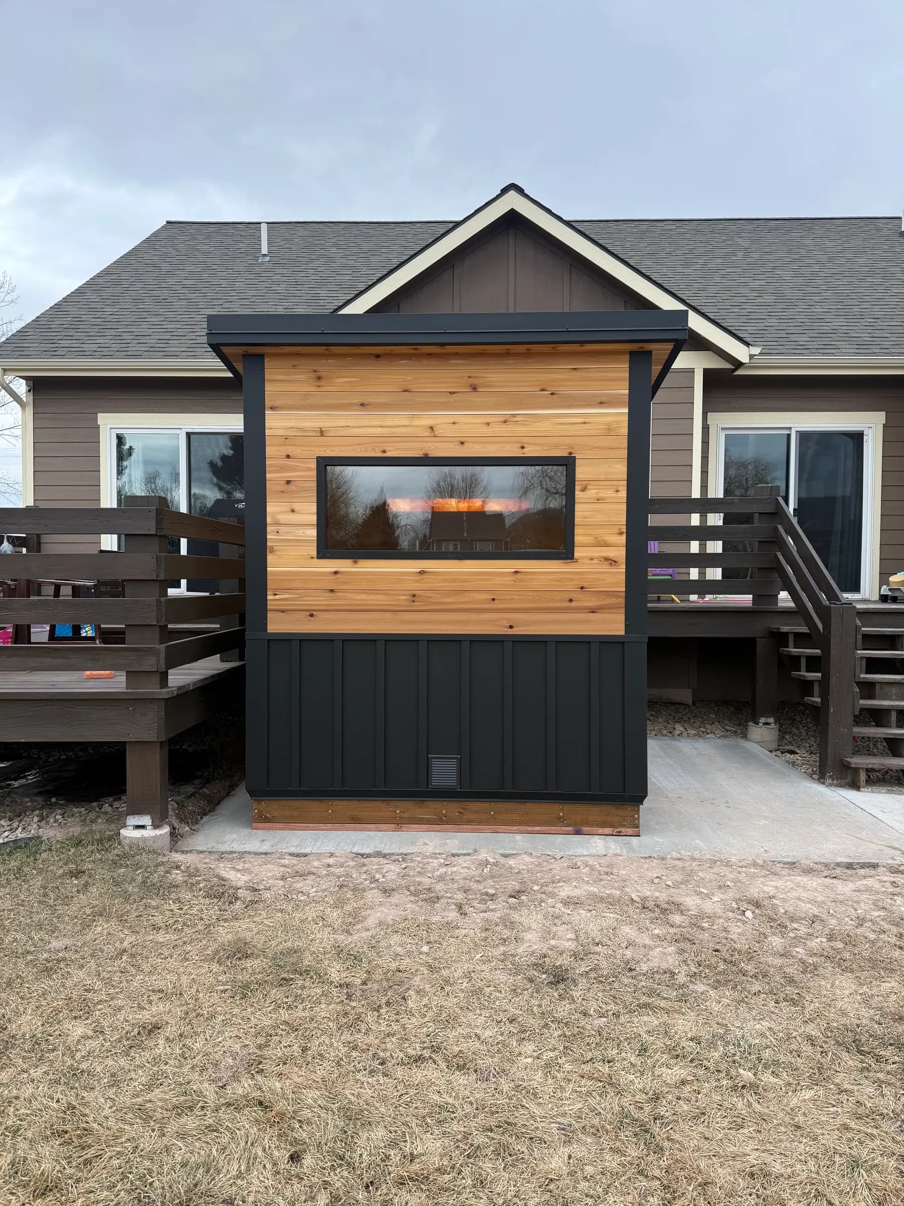 Ryne Dougherty’s Model T with cedar and black siding and a wide window, on a concrete pad behind the house