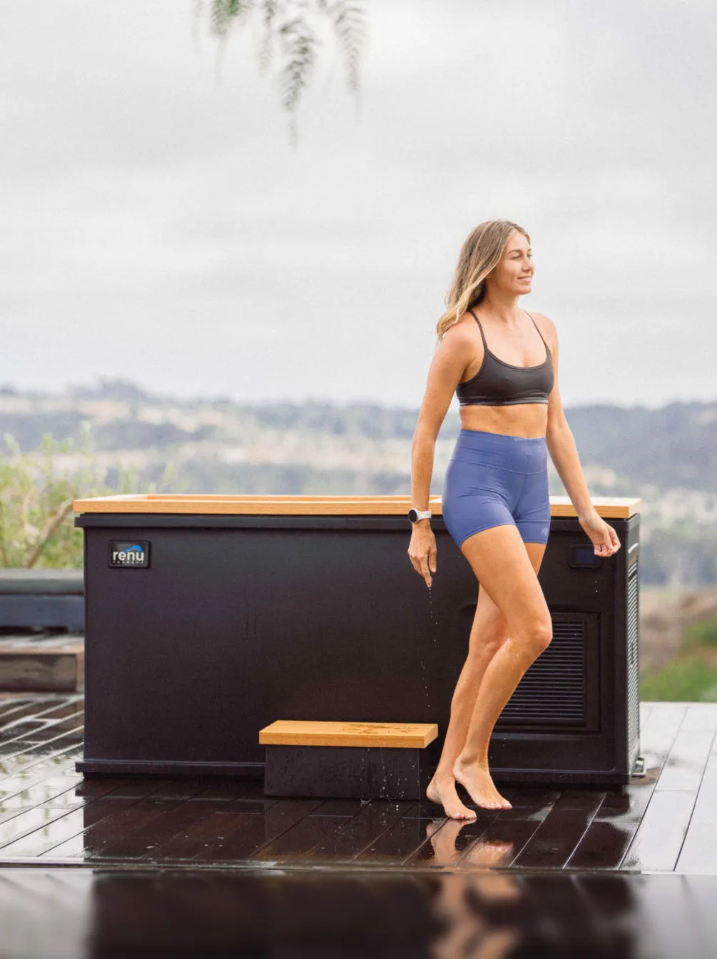 Woman standing beside a black Cold Stoic with a teak deck on an outdoor deck