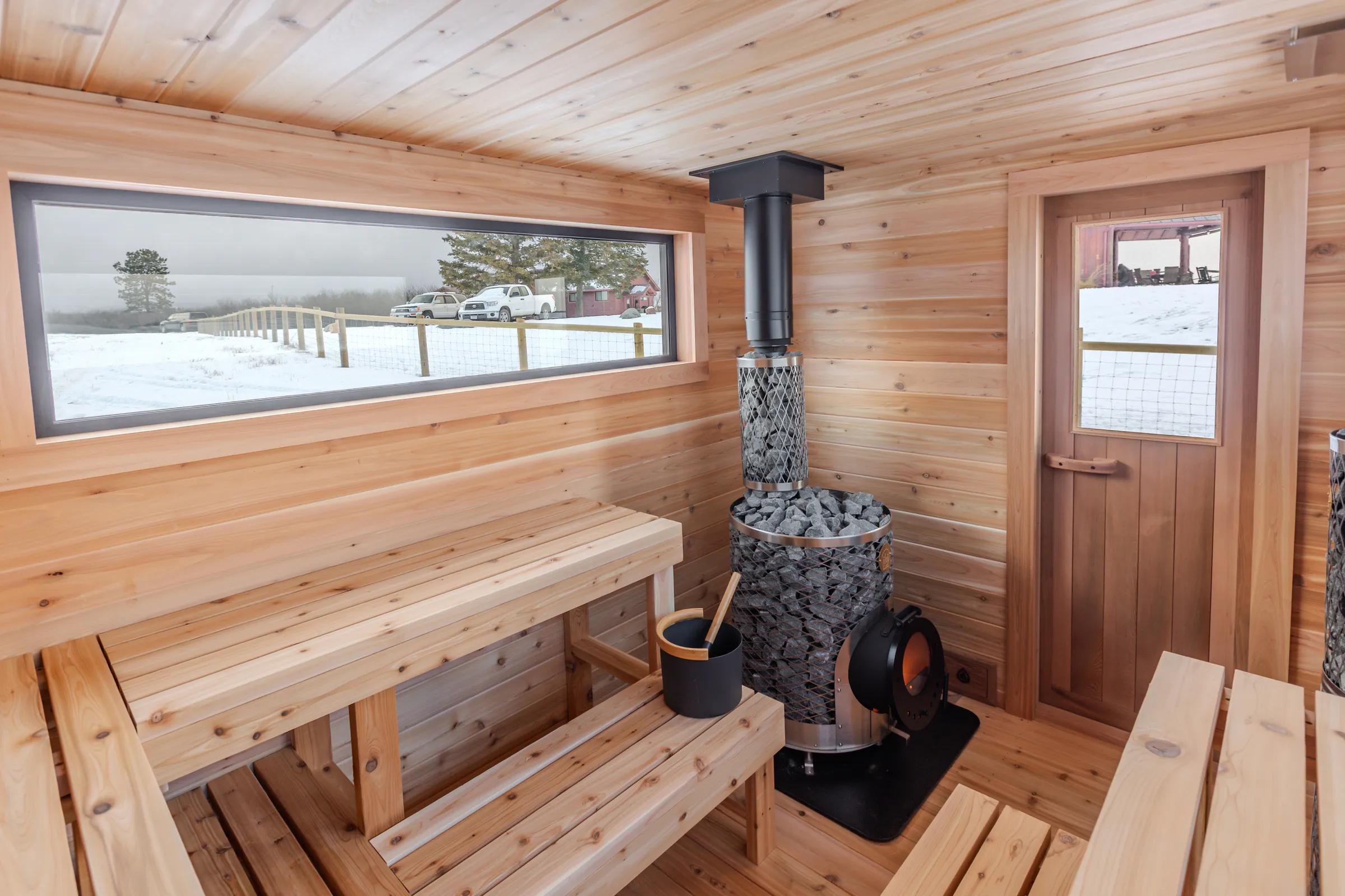Cedar interior with a long window, wood stove and glass-panel door