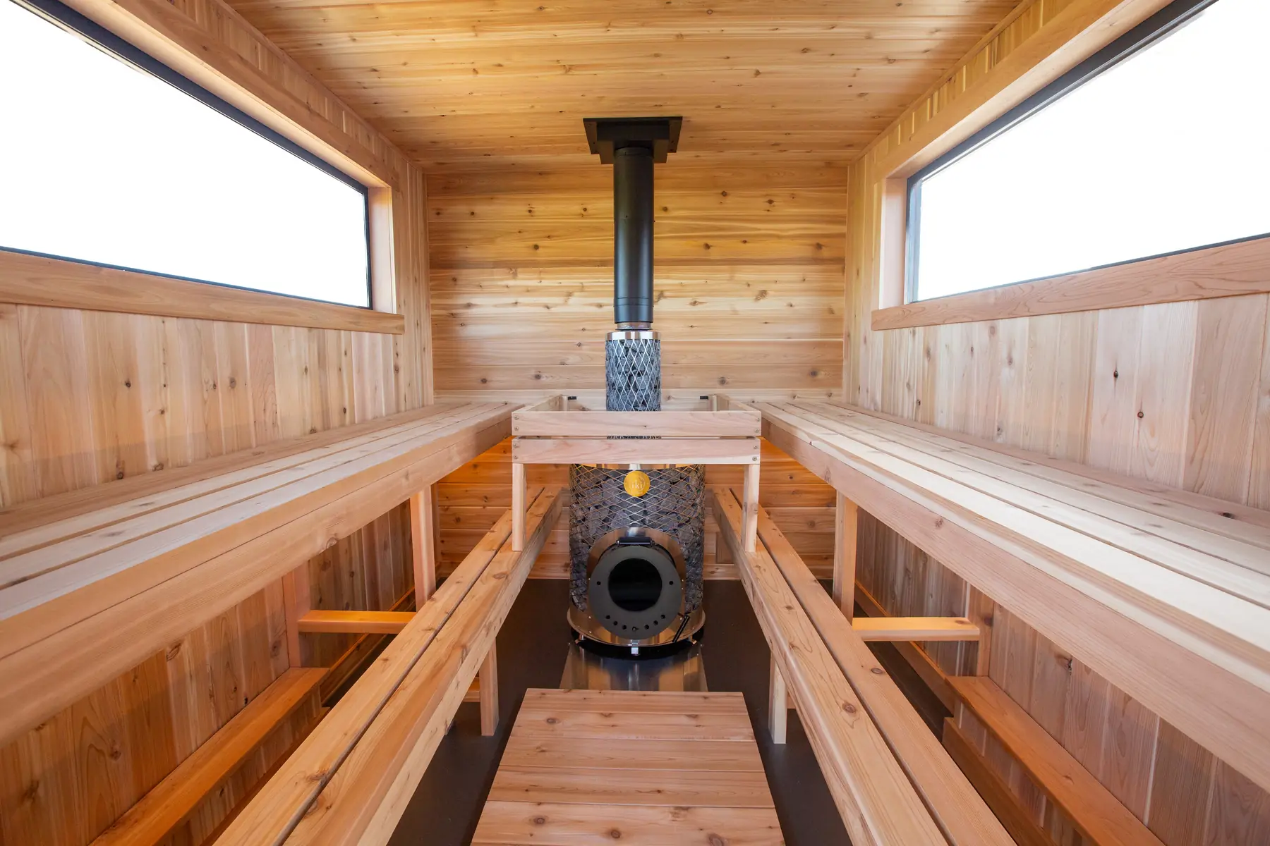 Inside the Mobile 10: cedar benches on both sides of the wood stove, windows above
