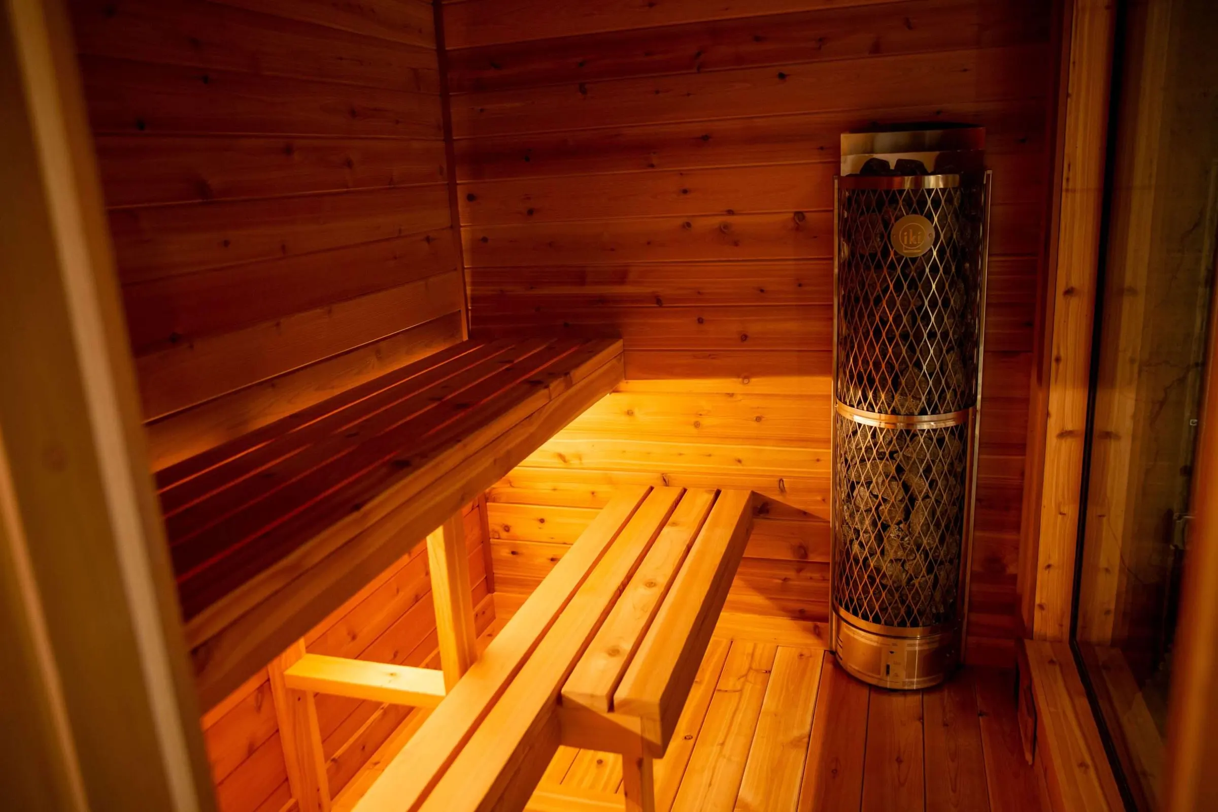 Cedar indoor sauna with lit benches and an electric heater