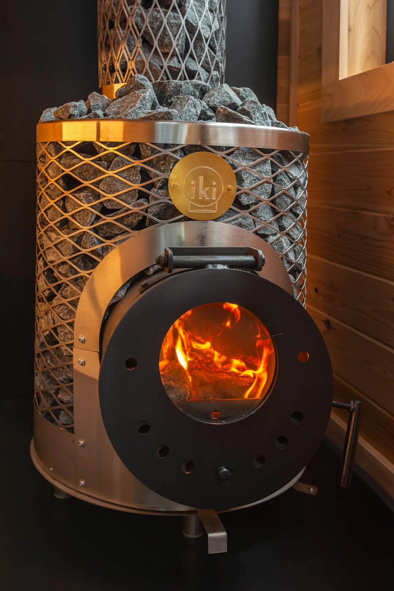 Wood-fired IKI stove with its stone cage, fire lit