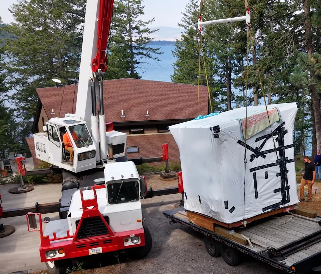 Crane lifting a wrapped sauna off a trailer