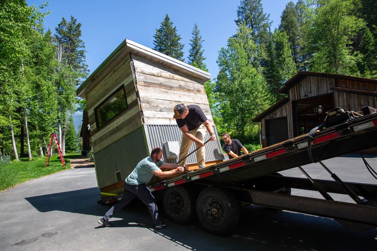 Crew sliding a finished sauna off a delivery trailer