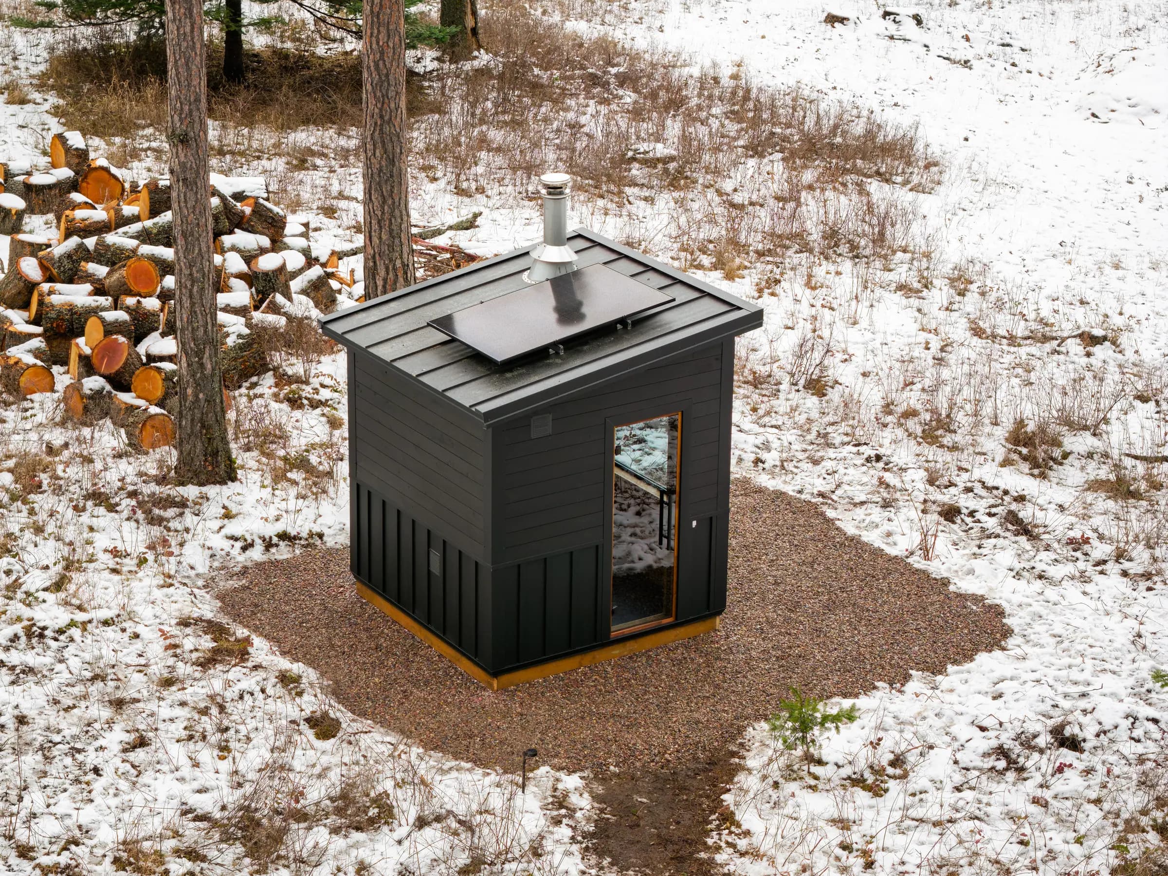 Aerial view of a black Model T with a roof solar panel on a gravel pad in the snow