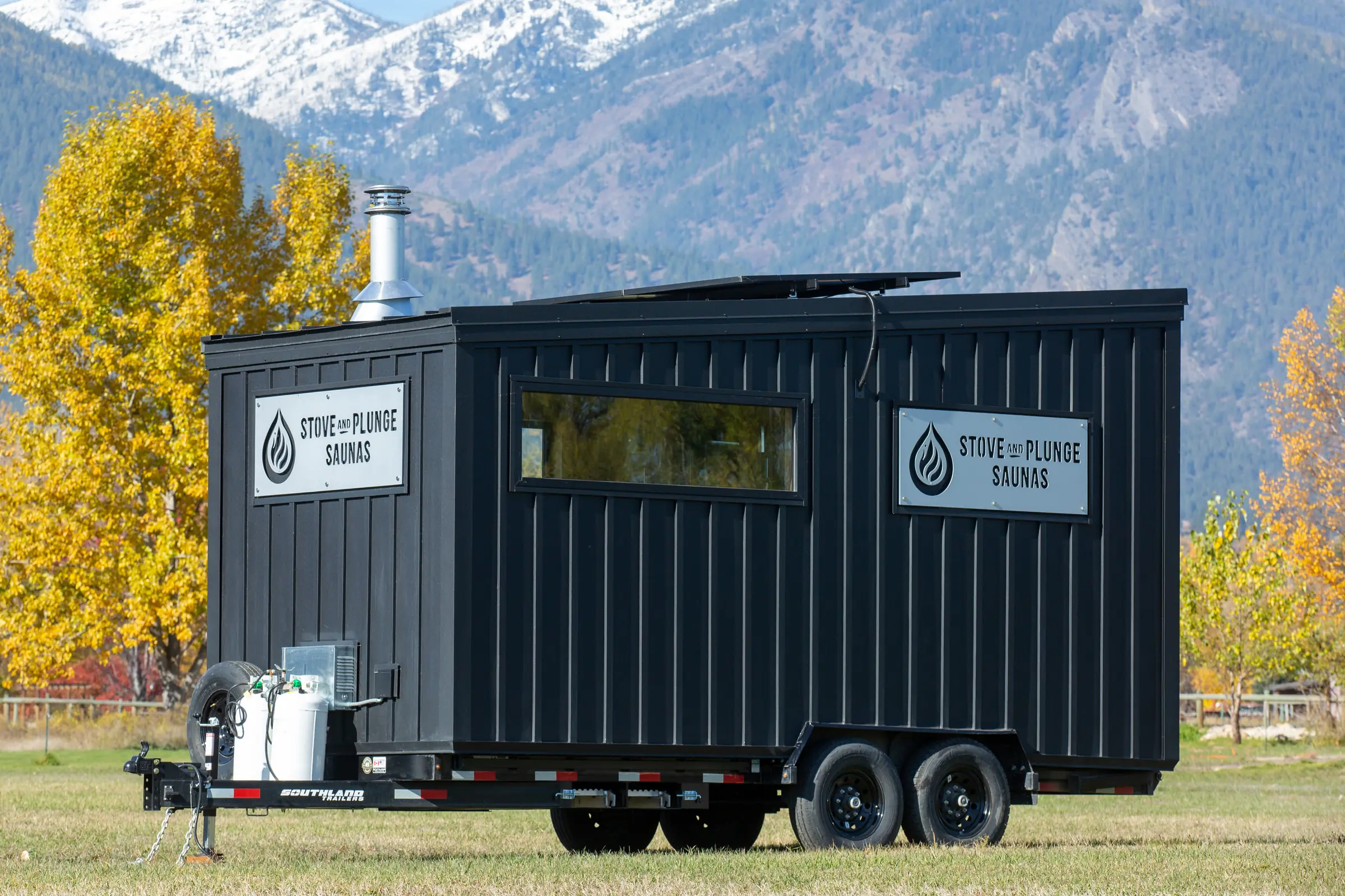 Mobile 10C on its trailer in a field, autumn trees and snowy mountains behind