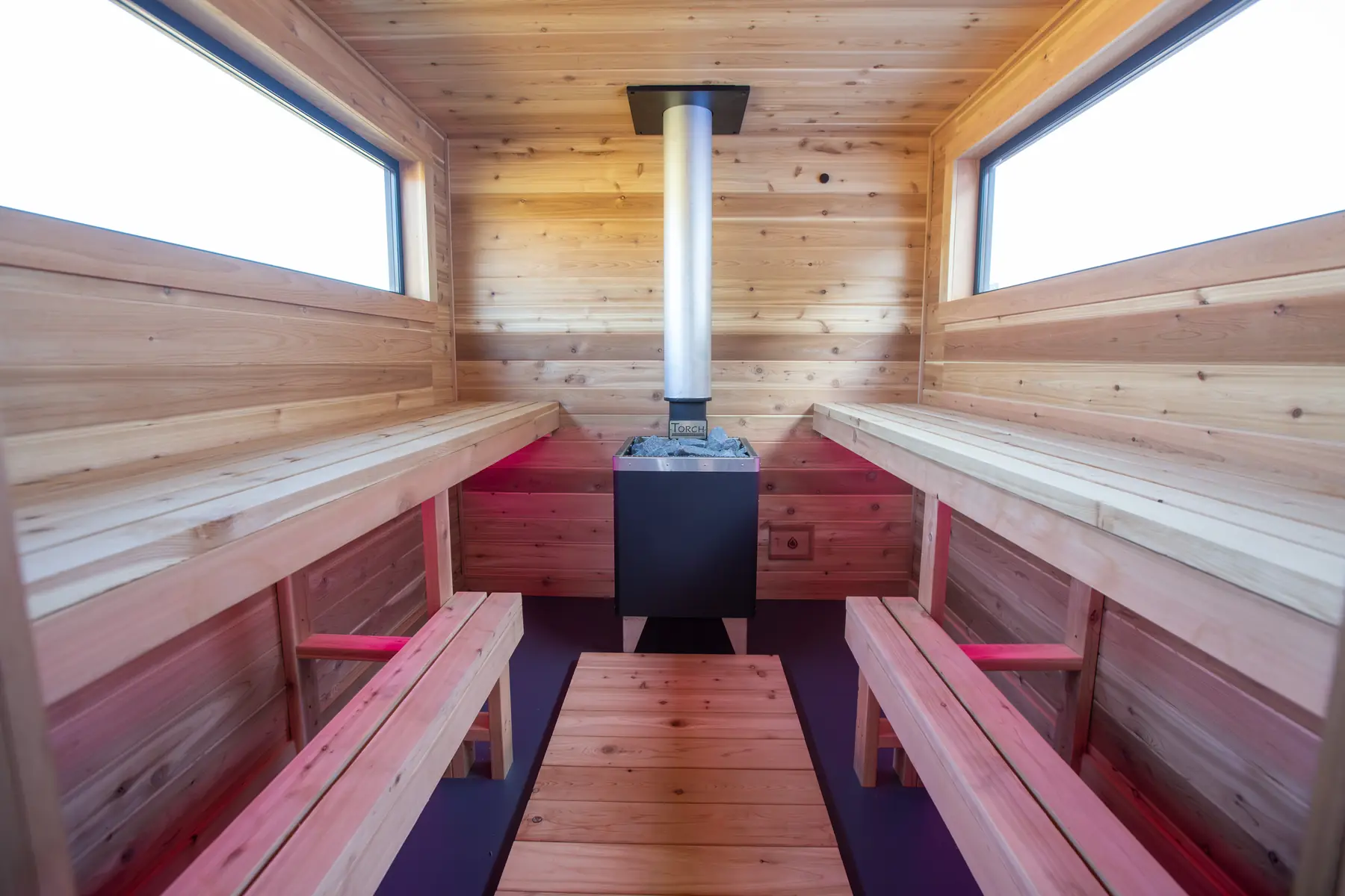 Inside the Mobile 10C: cedar benches on both sides of the stove, windows above
