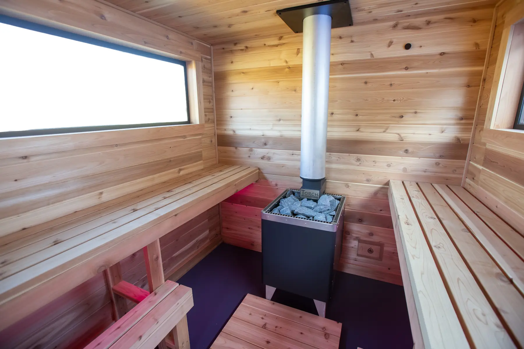 Inside the Mobile 10C: cedar benches around the stove under a long window