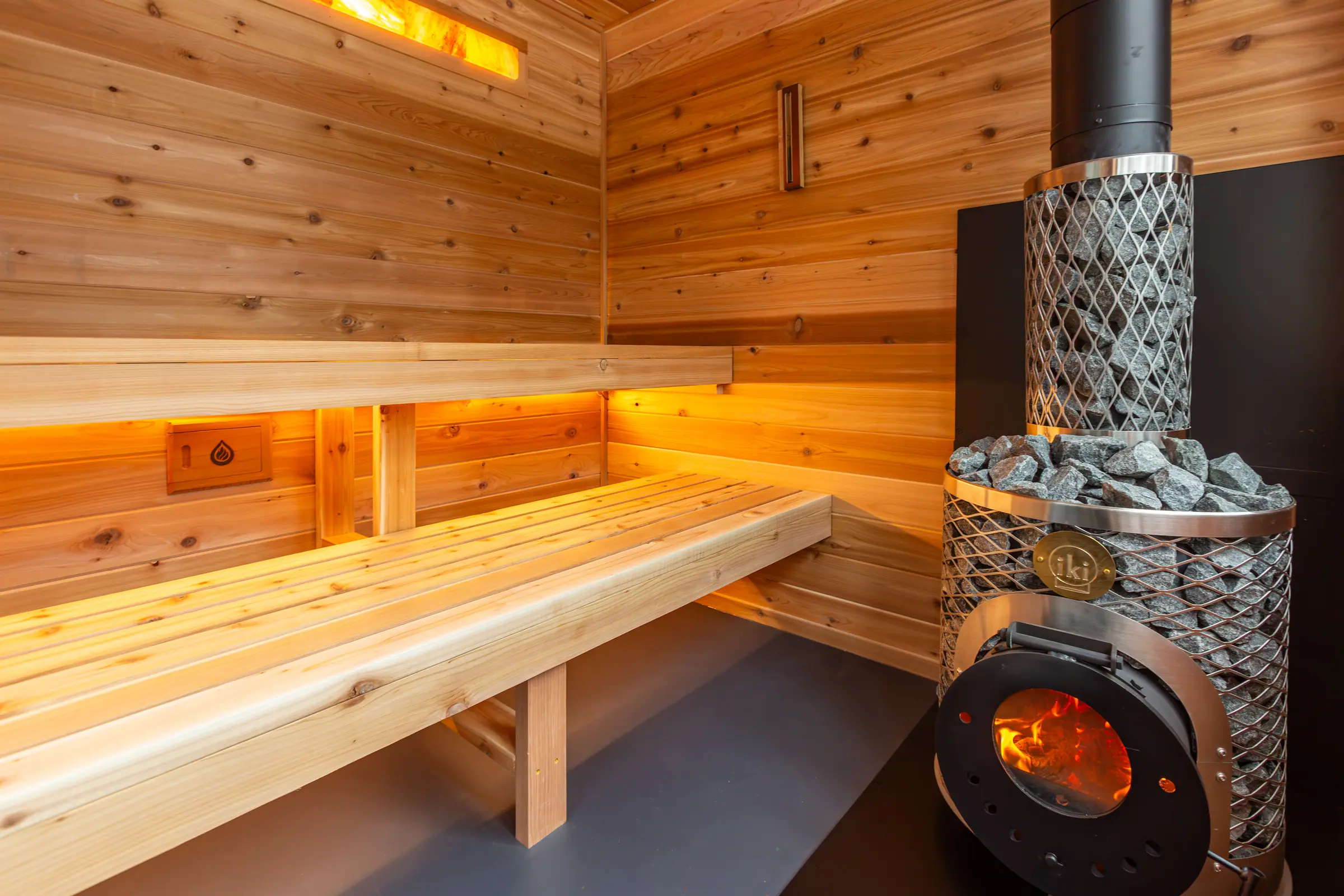 Wood-fired IKI stove beside lit cedar benches