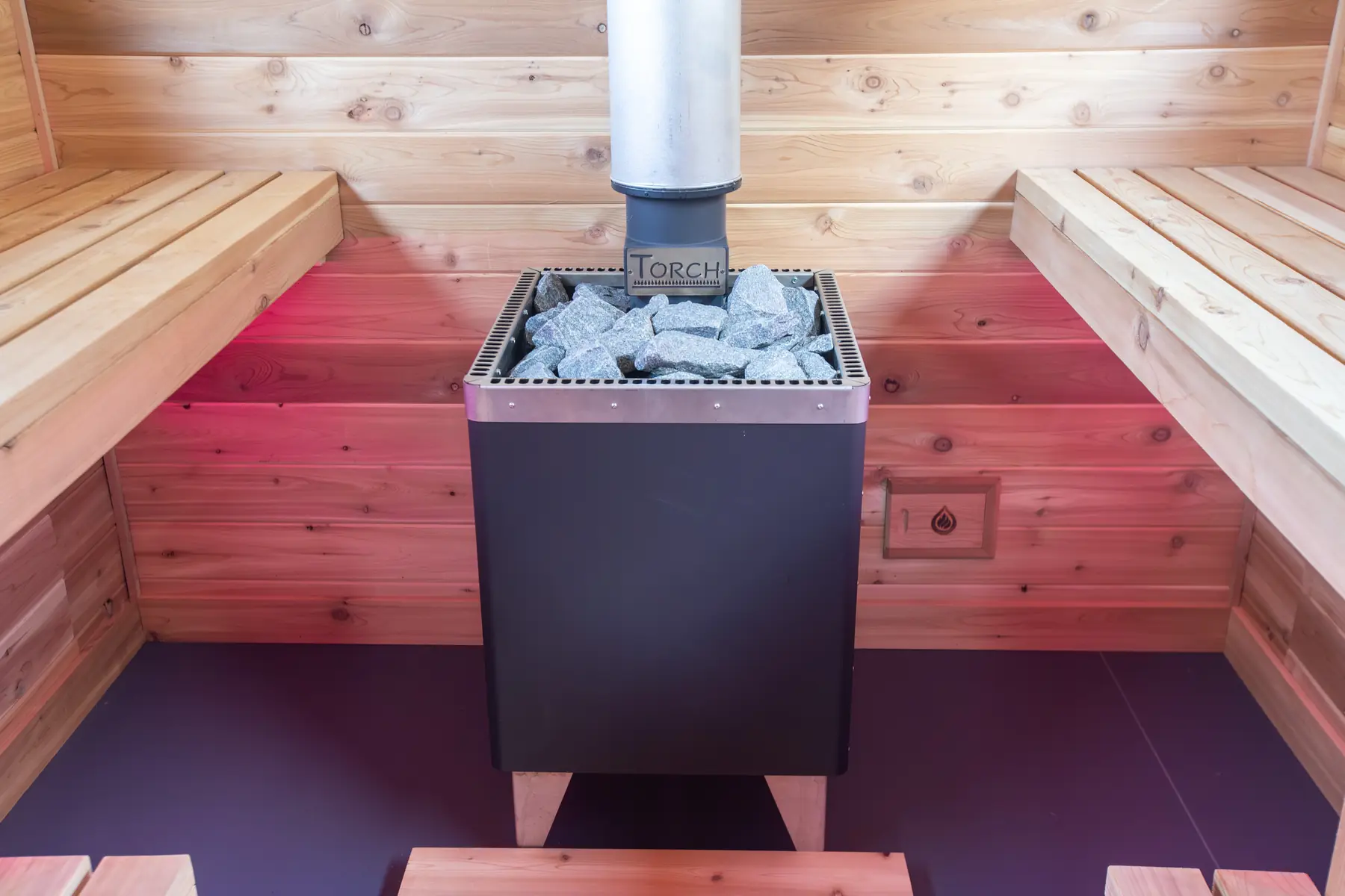 Torch T-80 propane sauna stove filled with stones between cedar benches